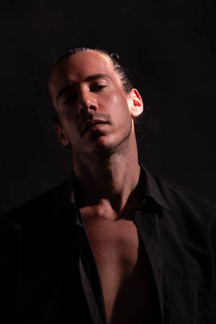 Low-angle close-up of Zeyan in an open black shirt. Colour portrait.